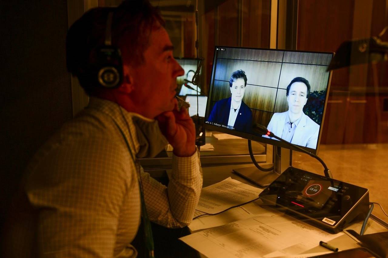 A translator works as WE Charity founders Marc Kielburger, screen left, and Craig Kielburger, screen right, appear as witnesses via videoconference during a House of Commons finance committee in the Wellington Building in Ottawa on Tuesday, July 28, 2020. The federal Conservatives are calling on WE Charity to release a series of documents that the Toronto-based youth organization promised to hand over to a House of Commons committee before Prime Minister Justin Trudeau prorogued Parliament. THE CANADIAN PRESS/Sean Kilpatrick