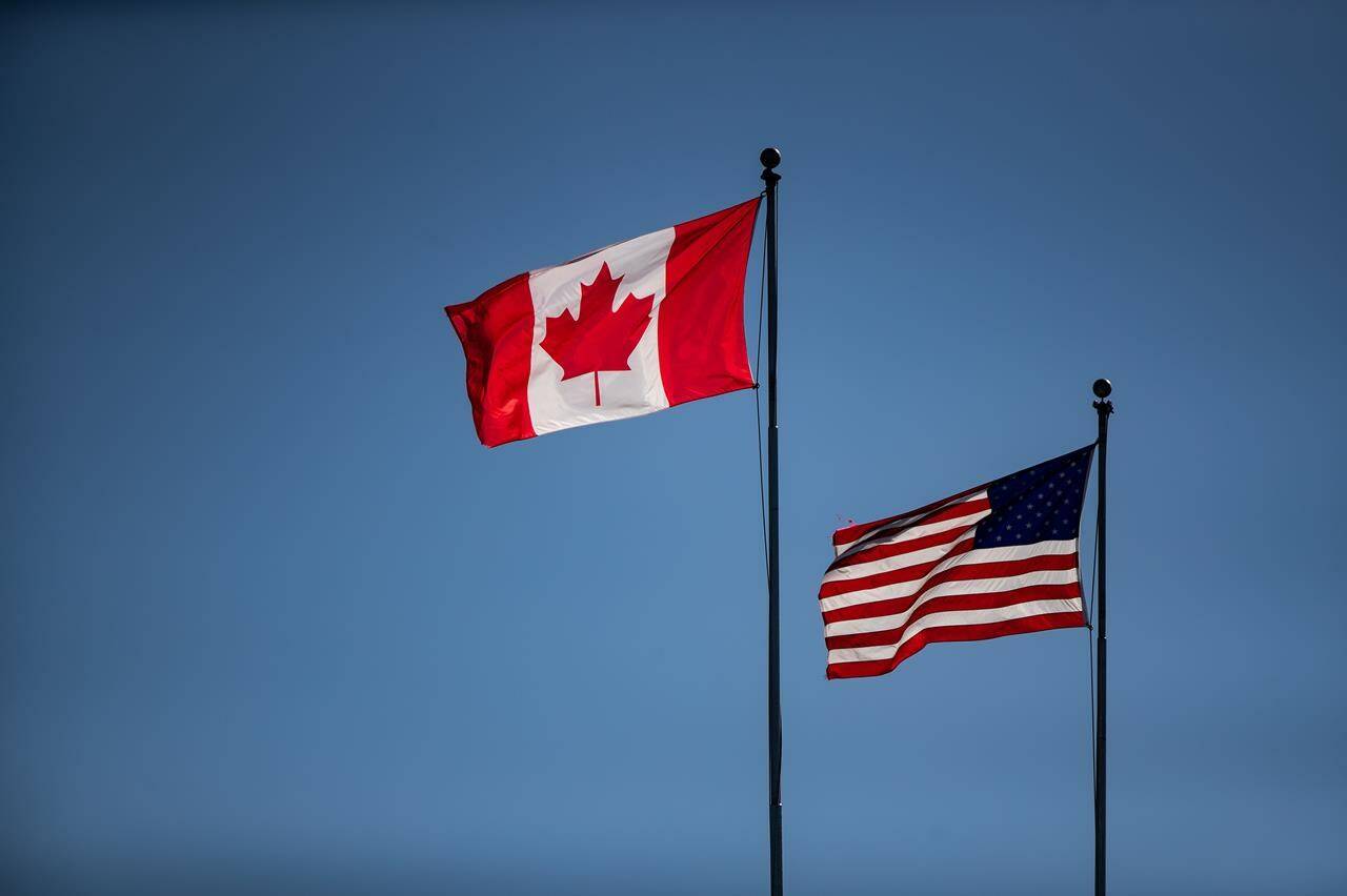 Canada and U.S. flags fly in the wind at the Douglas-Peace Arch border crossing, in Surrey, B.C., on Monday, March 16, 2020. The Canadian Chamber of Commerce wants federal leaders to get serious about making critical minerals a fundamental part of North America’s economic recovery. THE CANADIAN PRESS/Darryl Dyck