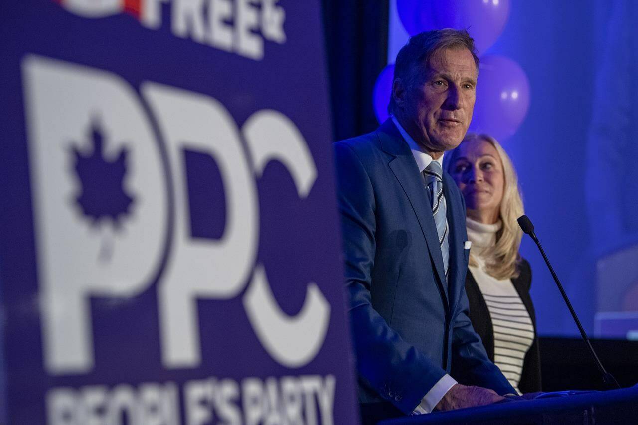 People’s Party of Canada Leader Maxime Bernier and wife Catherine Letarte speaks from a podium to supporters during the PPC headquarters election night event in Saskatoon, Sask., Monday, Sept. 20, 2021. THE CANADIAN PRESS/Liam Richards