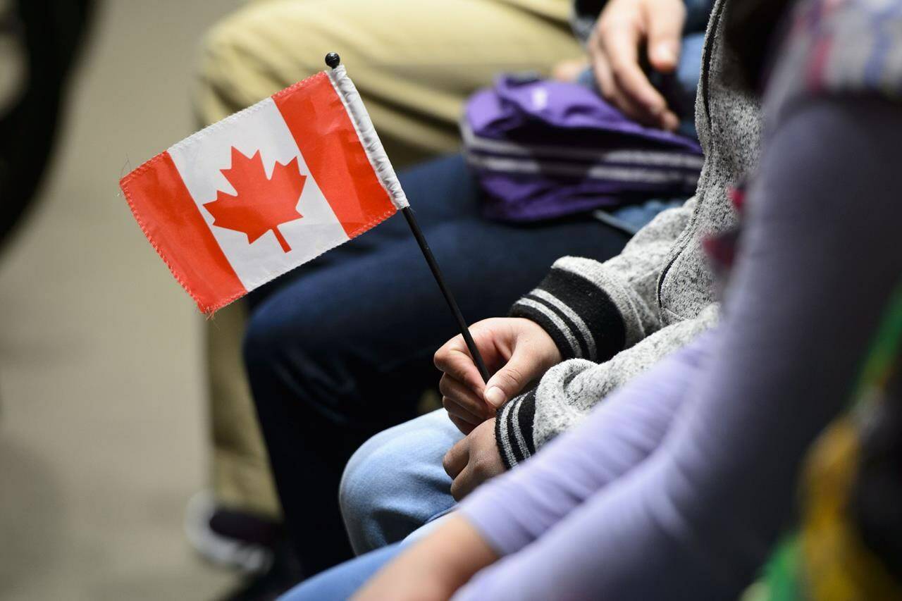 A young new Canadian holds a flag as she takes part in a citizenship ceremony on Parliament Hill in Ottawa on Wednesday, April 17, 2019. Canadians’ pride in their nationality, like most things these days, seems to be divided down partisan lines, a new poll suggests. THE CANADIAN PRESS/Sean Kilpatrick