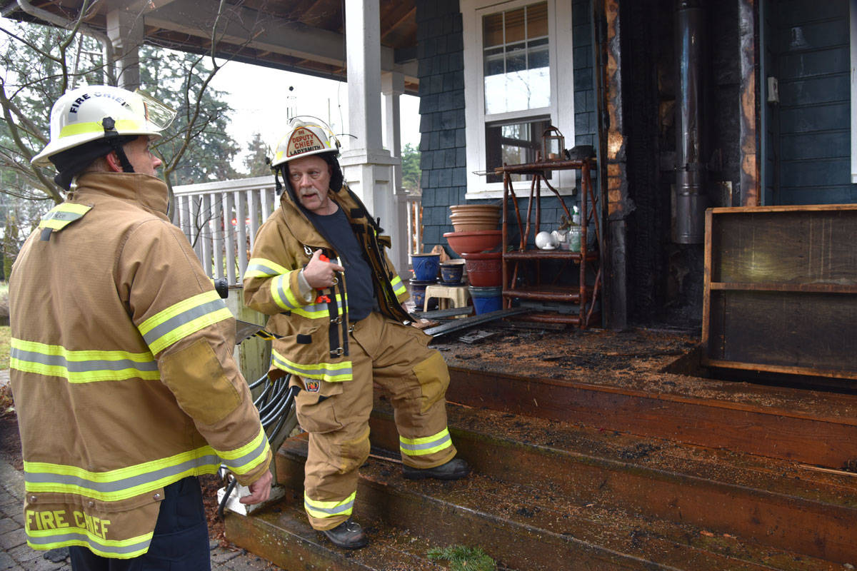 Fire Chief Ray Delcourt and Deputy Chief Al Delcourt examine the damage that was contained to the chimney. (Mike Gregory Photo)
