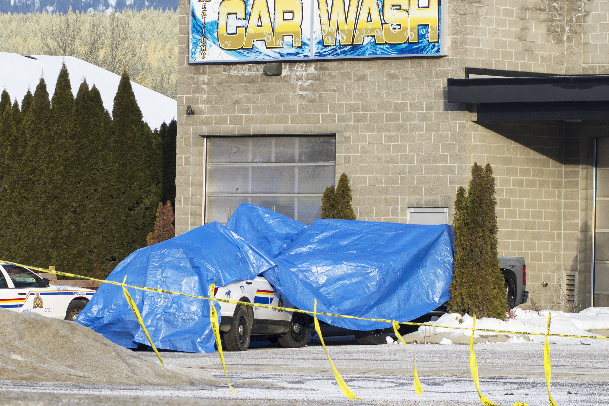 An RCMP vehicle and a grey pickup truck are tarped over in the parking lot of the car wash and Kawasaki dealership on Monday, Jan. 30, 2017 (File photo/Salmon Arm Observer)