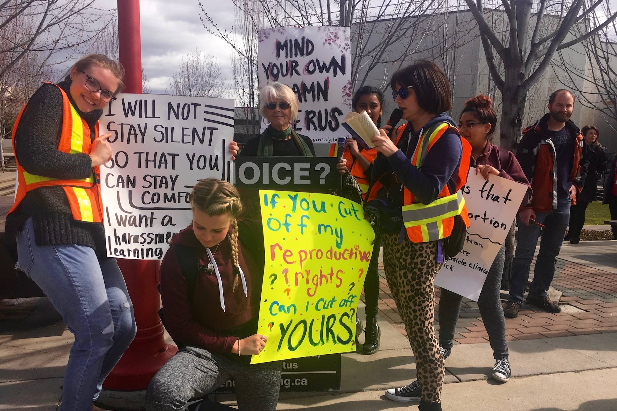 A college literary professor reads lines from The Bell Jar, by Syliva Path, to a Kelowna Right to Life demonstrator. The demonstrator’s sign is being blocked by the pro-life students surrounding her. (IMAGE CREDIT: CARMEN WELD)