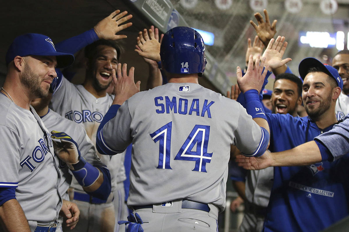 Toronto Blue Jays’ Justin Smoak is greeted in the dugout after scoring on a single by Yangervis Solarte in the fourth inning of a baseball game Monday, April 30, 2018, in Minneapolis. The Blue Jays won 7-5. Smoak had a two-run home run in the fourth inning. (AP Photo/Jim Mone)