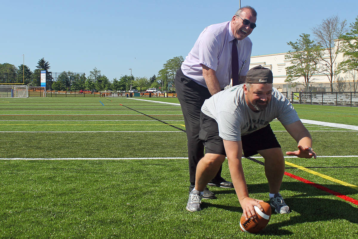 Nanaimo Ladysmith Public Schools superintendent John Blain, a former CFL player, and NDSS football coach Nate Stevenson get ready to run a play on the new artificial turf field at NDSS. TAMARA CUNNINGHAM/News Bulletin