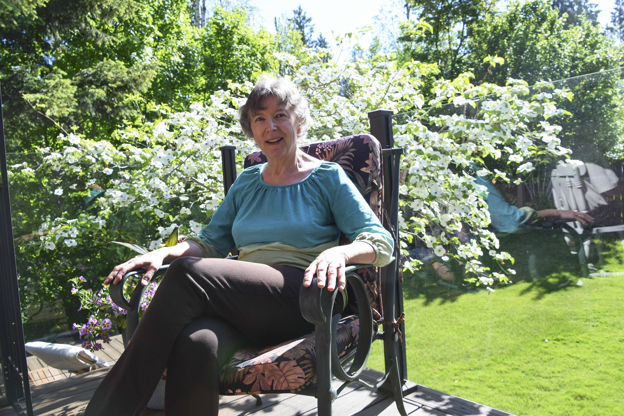 Maureen Kennah-Hafstein sits in front of her favourite dogwood tree in her backyard. Medication and supplements help to control some of her symptoms but each night she endures a painful withdrawal with uncontrollable movement and spasms. (Tracy Hughes/Salmon Arm Observer)
