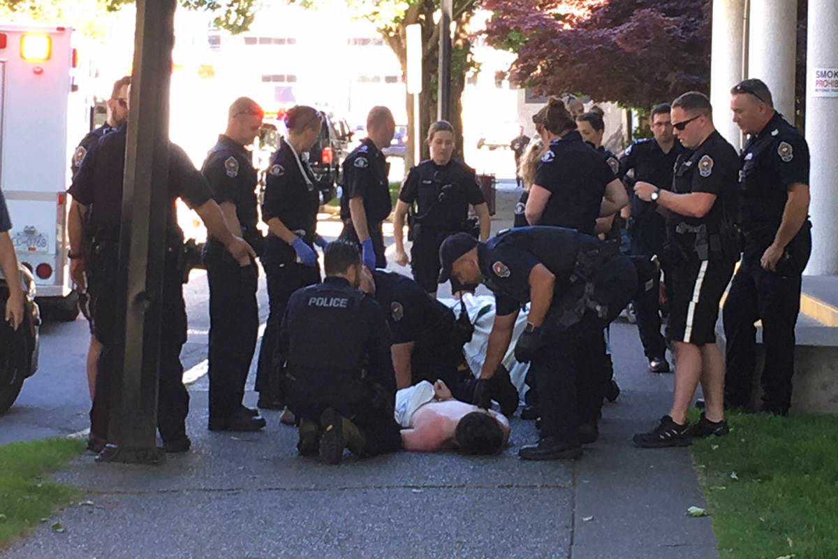 Victoria police officers and paramedics surround a man likely to face charges relating to a disturbance in Floyd’s Diner and the later assault of a man outside the Ministry of Health building at Blanshard Street and Pandora Avenue on Wednesday morning. Ragnar Haagen/BLACK PRESS