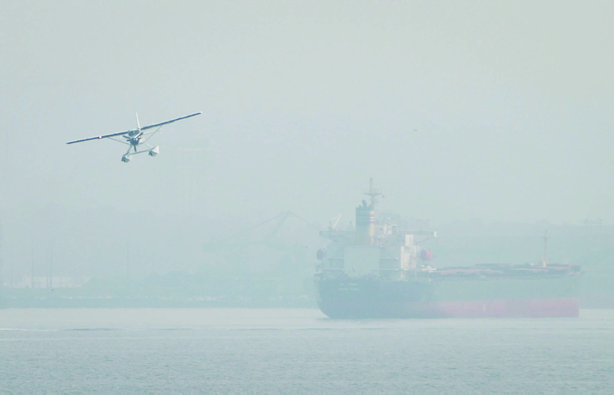 Smoke from wildfires burning in central British Columbia hangs in the air as a seaplane prepares to land on the harbour near the bulk carrier Nanakura, in Vancouver, B.C. in 2017. Flights have been grounded between Victoria, Vancouver and Richmond due to poor visibility. File photo