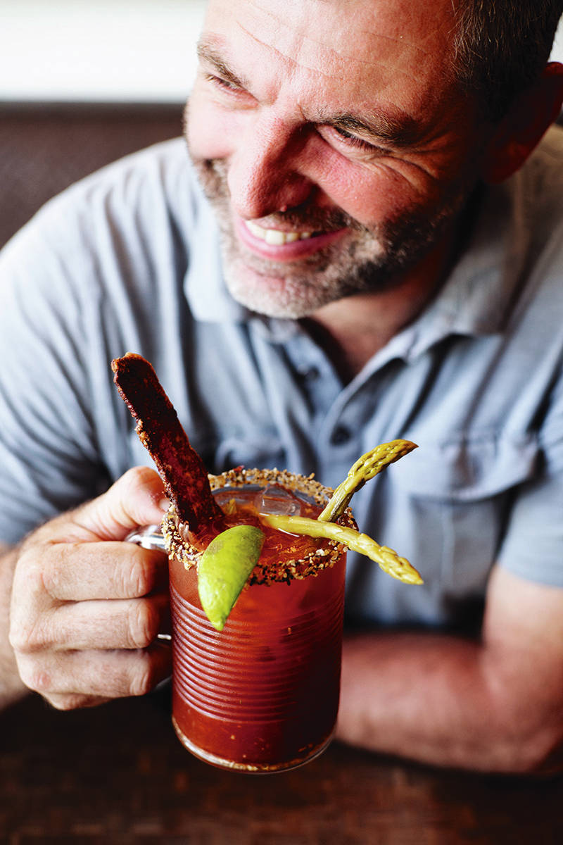 Jam Cafe owner Jim Walmsley holds a Classic Jam Caesar with a bacon garnish. (Lia Crowe photograph)