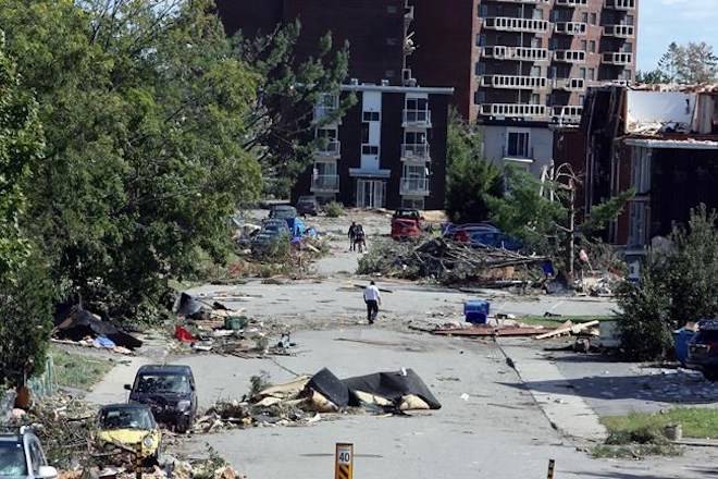 People walk past debris in a Gatineau, Que. neighbourhood on Saturday, September 22, 2018. A tornado on Friday afternoon tore roofs off of homes, overturned cars and felled power lines in the Ottawa community of Dunrobin and in Gatineau, Que.                                THE CANADIAN PRESS/Fred Chartrand