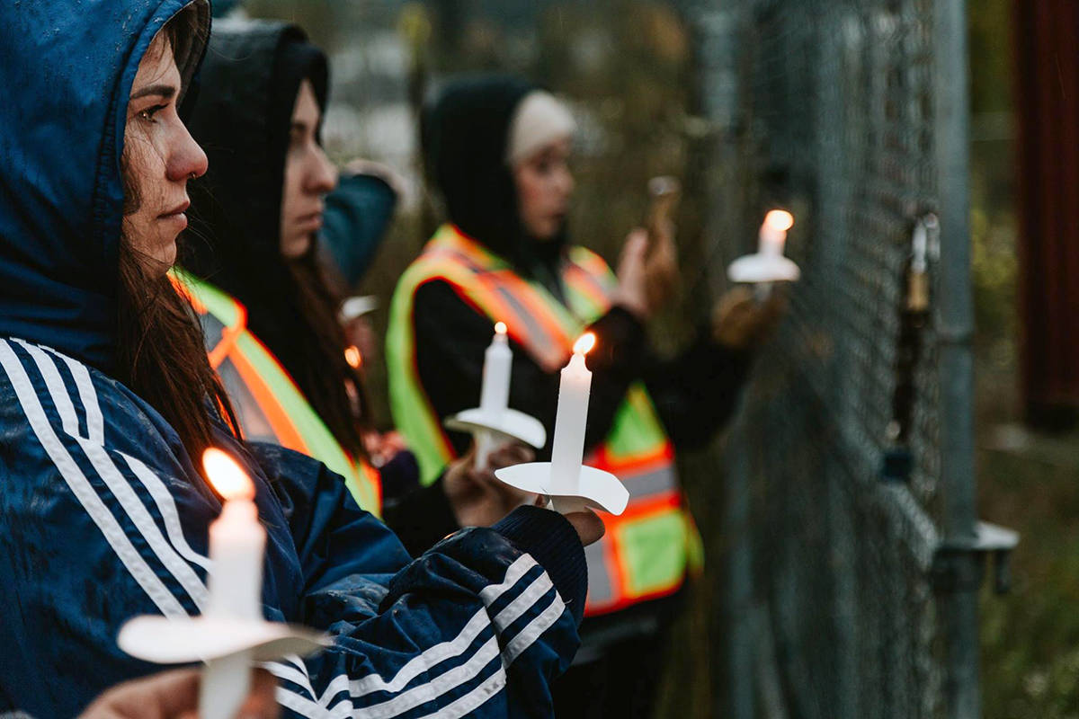 A group of activists with the Okanagan Animal Save group hold lit candles near the fence surrounding the Rocana Meats facility in Salmon Arm during a protest Monday, Oct. 1. (Facebook/Okanagan Animal Save)