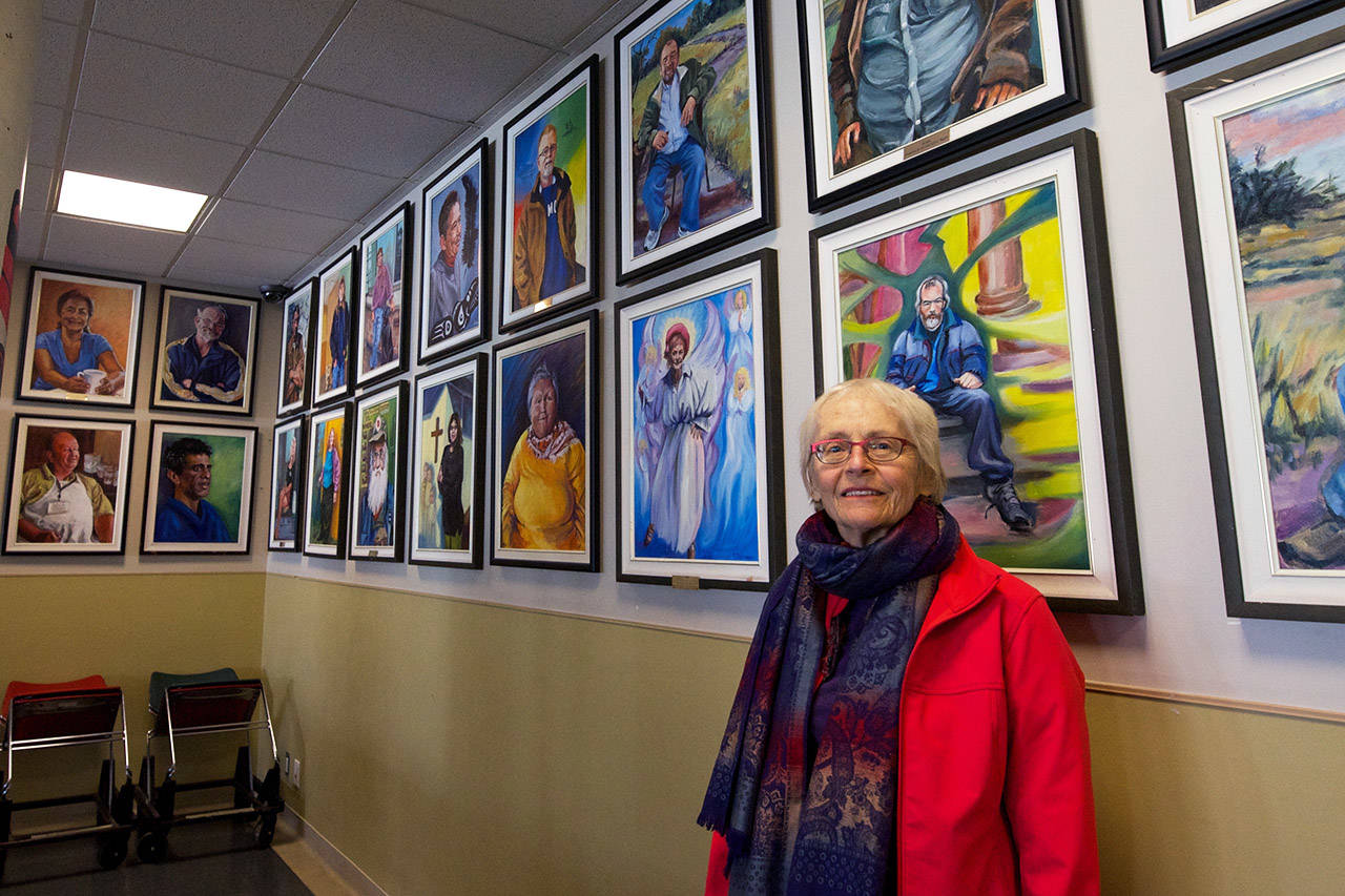 Elfrida Schragen stands in front of some of the portraits she painted of frequent visitors to Our Place. (Nicole Crescenzi/News Staff)