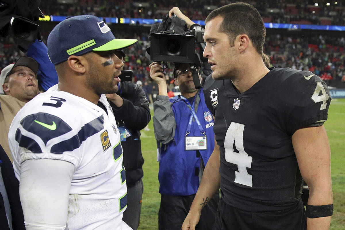 Seattle Seahawks quarterback Russell Wilson (3), left, and Oakland Raiders quarterback Derek Carr (4), chat at the end of an NFL football game at Wembley stadium in London, Sunday, Oct. 14, 2018. Seattle Seahawks won the match 27-3. (AP Photo/Tim Ireland)