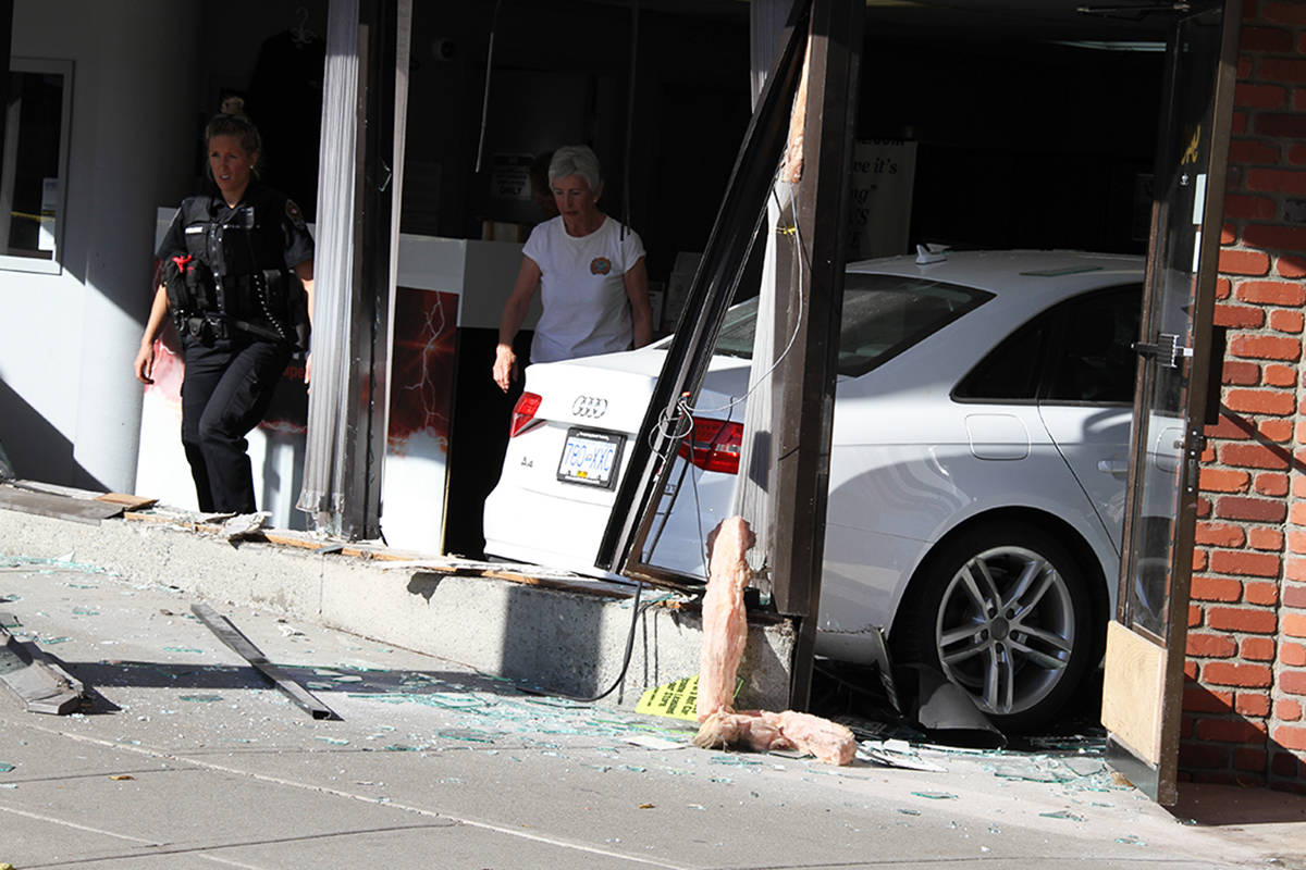 A Victoria police officer and a woman believed to be the driver of the white Audi that smashed through the window of a View Street business survey the damage Monday afternoon. (Kristyn Anthony/News staff)