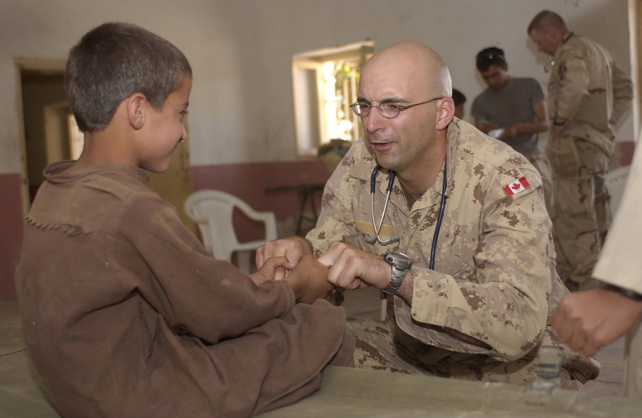 Master Corp. Eric Demers, a medic with the Canadian Provincial Reconstruction Team, jokingly grimaces as he asks a young boy to squeeze his fingers as part of an examination in Kandahar in September 2005. Now retired from the military, Demers says physician assistants could be a way to increase care for B.C. patients. (Photo by Sgt. Jerry Kean, Canadian Armed Forces)