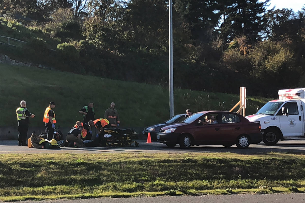 First responders help an injured motorcyclist after a collision involving three vehicles on the Pay Bay Highway, Wednesday. (Travis Paterson/News staff)