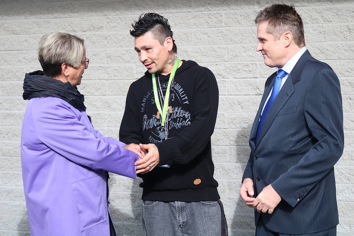 Judy Darcy (left), Minister of Mental Health and Addictions and Ryan L’hirondelle, support worker at Therapeutic Recovery Centre, shake hands while Don Evans, executive director of Our Place Society looks on. (Lindsey Horsting/News staff)