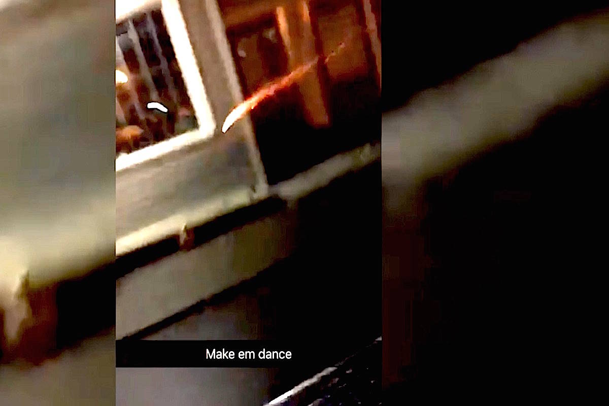 Still from video captioned ‘Make em dance’ shows exploding device thrown from vehicle at people huddled on Fletcher Street.