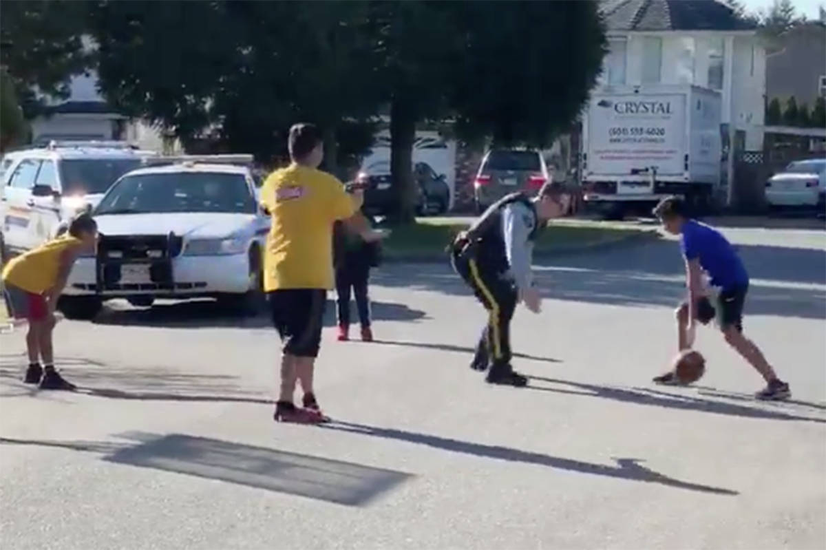 Surrey RCMP Corporal Brenden Vogt shoots hoops with some local kids on Sunday, March 17. (Photo: Video screenshot)