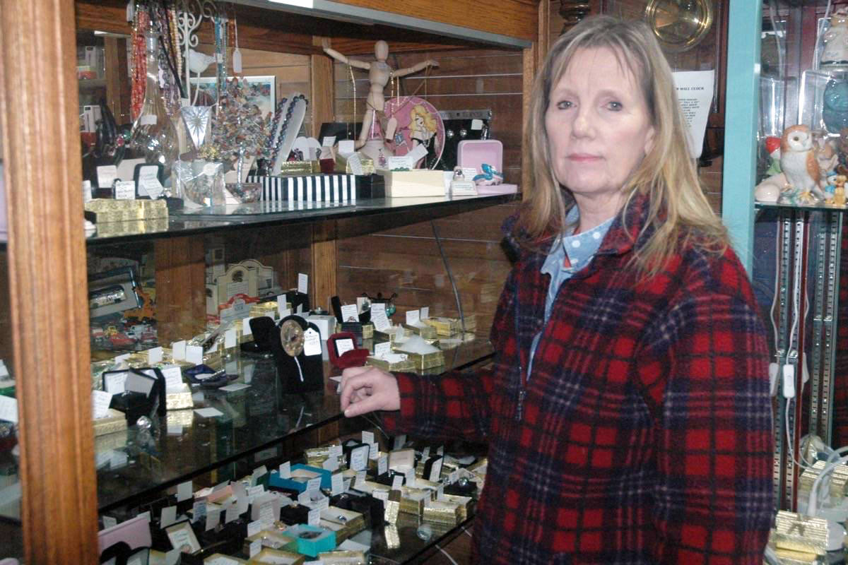 Liz Fincham, co-owner of Magpies Antiques in Chemainus, picks glass out of a display case after thieves broke in early Friday morning and stole more than $30,000 in jewelry. (Photo by Robert Barron/Cowichan Valley Citizen)
