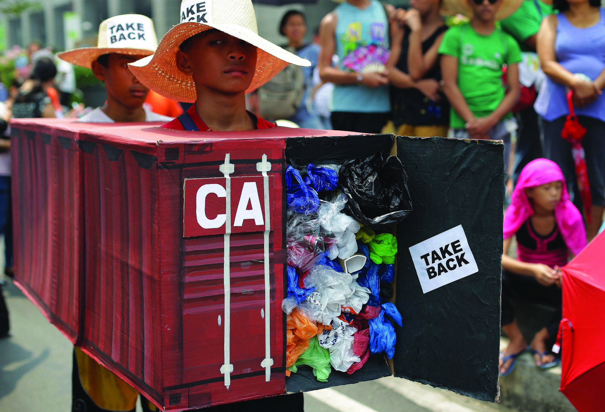 Filipino environmental activists wear a mock container filled with garbage to symbolize containers of waste that were shipped from Canada to the Philippines, as they hold a protest outside the Canadian embassy at the financial district of Makati, south of Manila, Philippines on Thursday, May 7, 2015. THE CANADIAN PRESS/AP/Aaron Favila