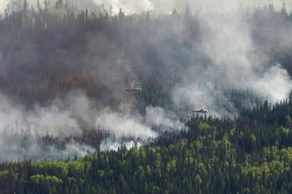 A helicopter drops a bucket of water on the Chuckegg Creek wildfire west of High Level, Alta., in a Saturday, May 25, 2019, handout photo. THE CANADIAN PRESS/Government of Alberta, Chris Schwarz