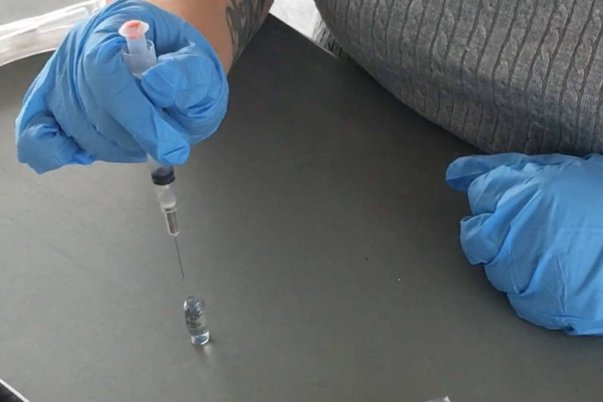 A community wellness worker demonstrates the use of a Naloxone kit. File photo