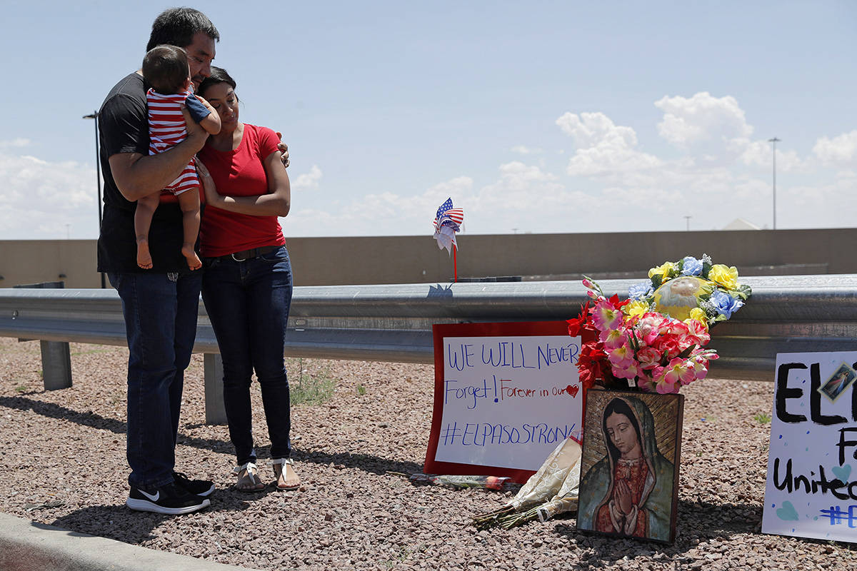 Dr. Julio Novoa, left, and Danielle Novoa, right, visit a makeshift memorial with their 10-month-old son Richard Novoa at the scene of a mass shooting at a shopping complex Sunday, Aug. 4, 2019, in El Paso, Texas. (AP Photo/John Locher)