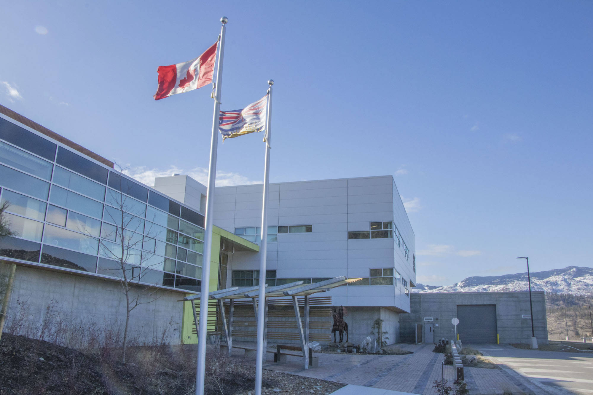 Flags fly outside the Okanagan Correctional Centre’s offices, which line the front of the building, behind windows near the public entrance to the jail. (Western News file photo)