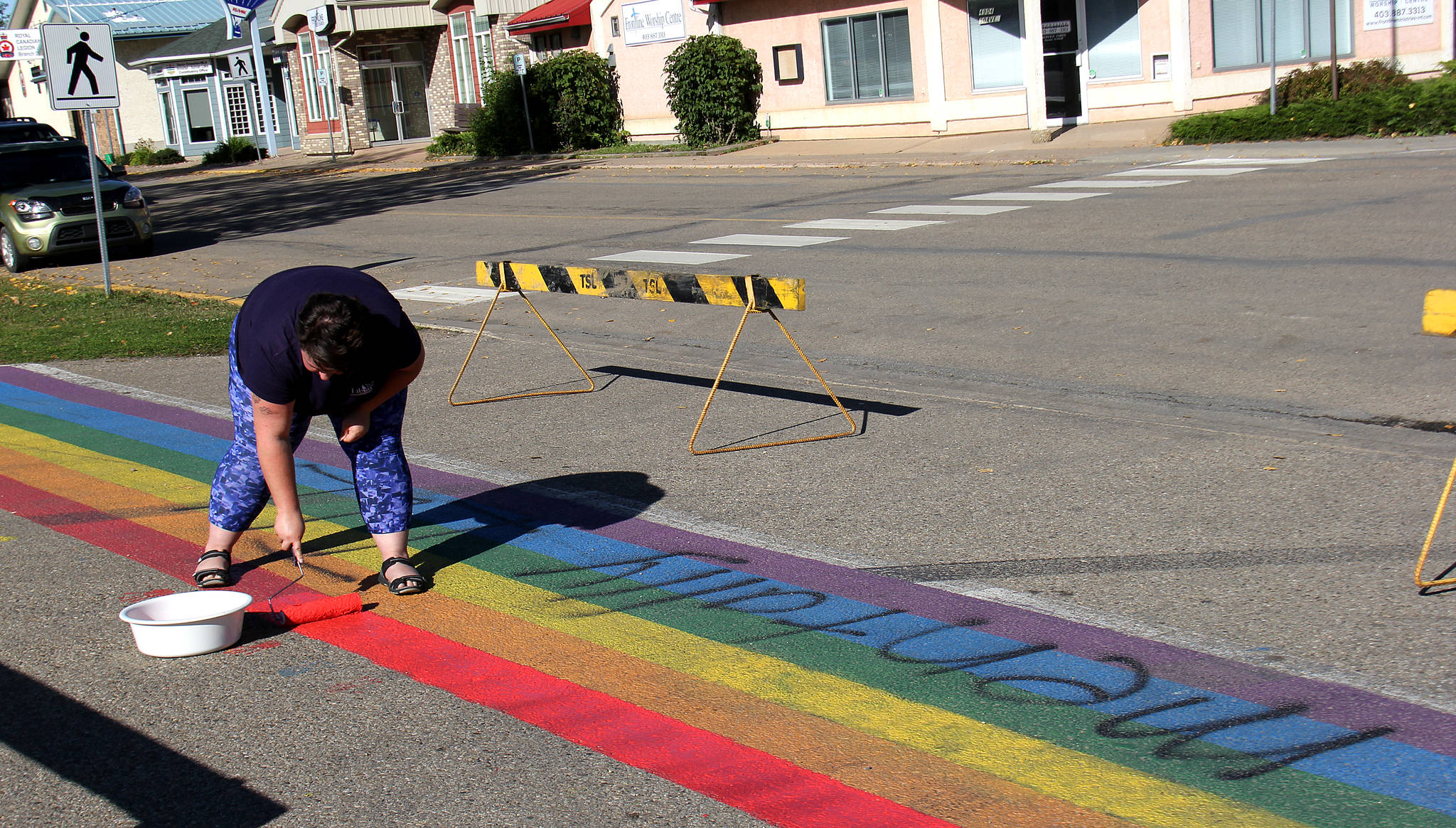 Corrie Brown gets to work repainting the rainbow crosswalk Thursday morning, after it was defaced with the words ‘metally ill” written in spray paint. This is the fourth time the cross walk has been repainted since it was first done in June. Photo by Megan Roth/Sylvan Lake News