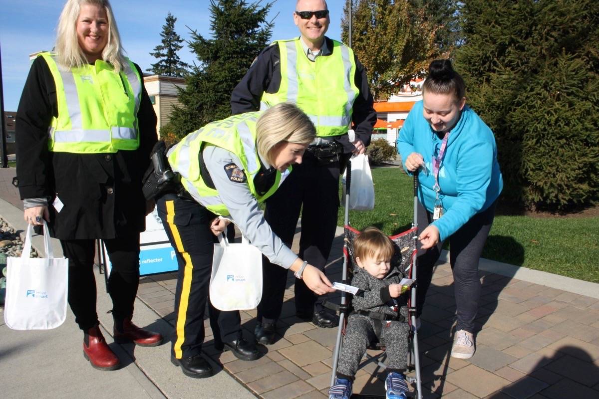 Cindy Larson and son Issac got their own reflective stickers on Monday from RCMP Staff Sgt. Brett Stinden, Const. Sam Haldane, second from left, and ICBC road safety coordinator Colleen Woodger. The stickers are part of ICBC’s road safety initiative. (Tim Collins/Sooke News Mirror)