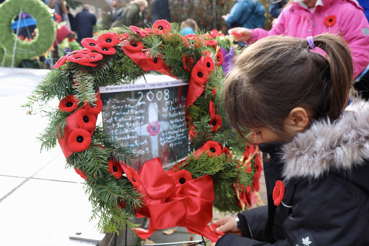 Elizabeth Chow adds extra poppies to the home-made wreath she made with her younger sister, Catherine, at Veterans Memorial Park in Langford. (Aaron Guillen/News Staff)