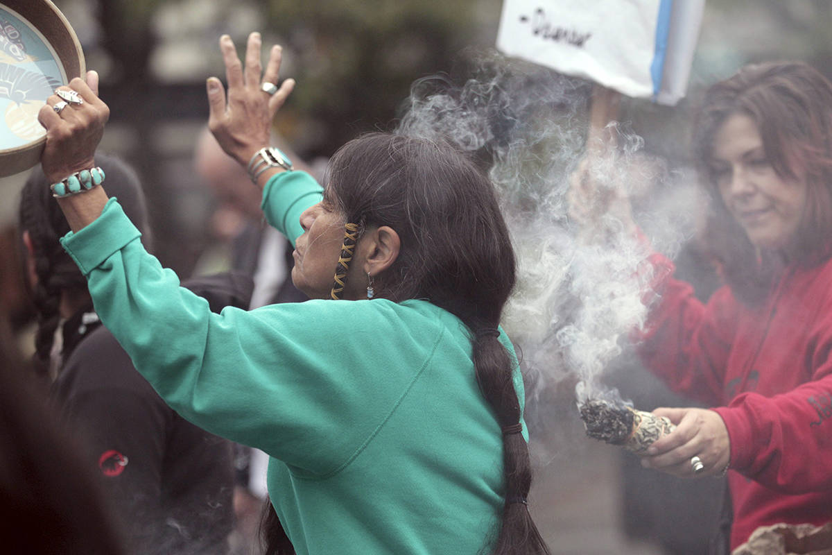 Ferntree, of Duncan, British Columbia, a member of the Cowichan Tribes, holds her hand up as she partakes in a smudging ceremony as smoke from a smoldering bundle of dried sweetgrass is directed toward her during a Native American protest against Columbus Day, Monday, Oct. 10, 2011, in Seattle. The fourth annual protest by the Oldgrowth Alliance included leaders and youth from Native American and Alaska Native communities speaking out against the annual holiday honoring Christopher Columbus’ arrival in the Americas. Protest organizers say that Columbus could not have “discovered” a western hemisphere already inhabited by about 100 million people. (AP Photo/Elaine Thompson)