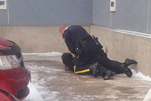 RCMP Const. Darrin Meier on top of Irene Joseph next to Mark’s Work Warehouse on Dec. 6, 2014. (File photo)