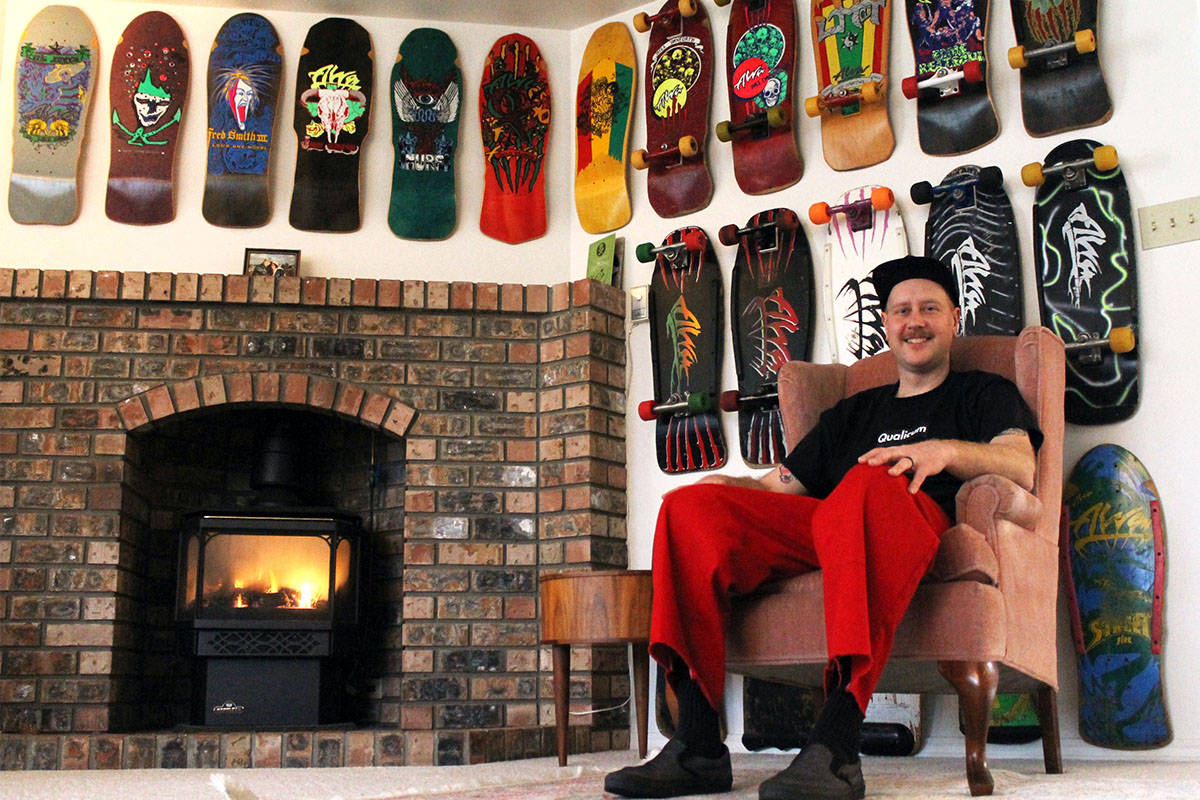 In Eric Pinto’s Qualicum Beach home, the walls are lined with historic skateboards, many of them full setups of era-accurate components. Pictured behind Pinto is a collection of Alva Skates boards. (Emily Vance photo)