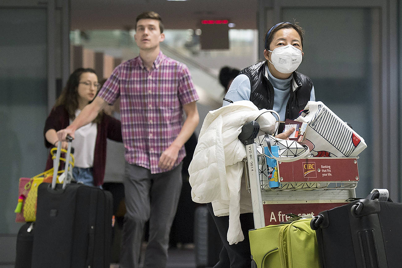A woman wears a mask following the outbreak of a new virus as people arrive from the International terminal at Toronto Pearson International Airport in Toronto on Saturday, Jan. 25, 2020. (Nathan Denette/The Canadian Press via AP)