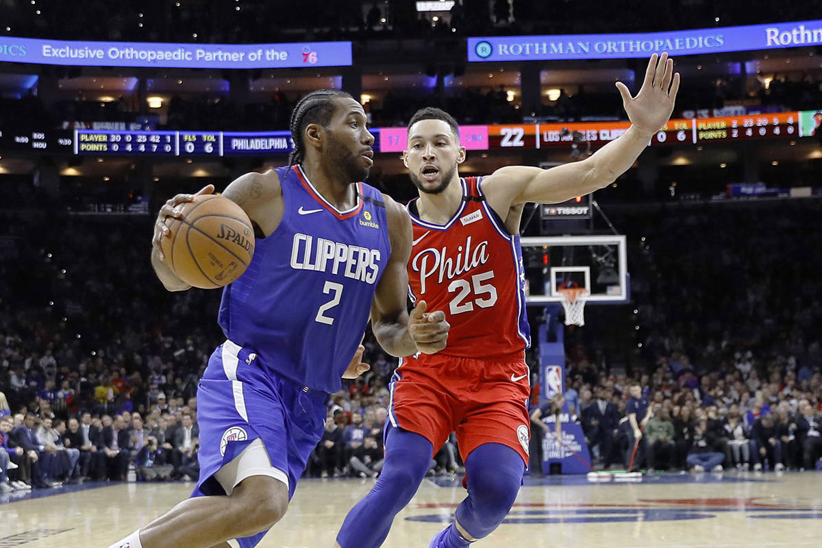 Los Angeles Clippers’ Kawhi Leonard, left, drives past Philadelphia 76ers’ Ben Simmons during the first half of an NBA basketball game, Tuesday, Feb. 11, 2020, in Philadelphia. (AP Photo/Matt Slocum)