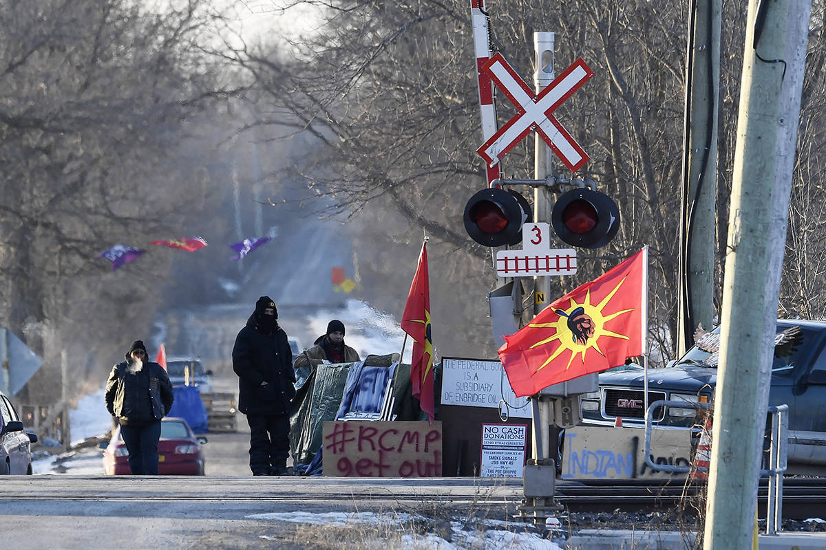 Protesters stand at a rail blockade in Tyendinaga Mohawk Territory, near Belleville, Ont., on Monday Feb. 24, 2020, during a protest in solidarity with Wet’suwet’en Nation hereditary chiefs attempting to halt construction of a natural gas pipeline on their traditional territories. THE CANADIAN PRESS/Adrian Wyld