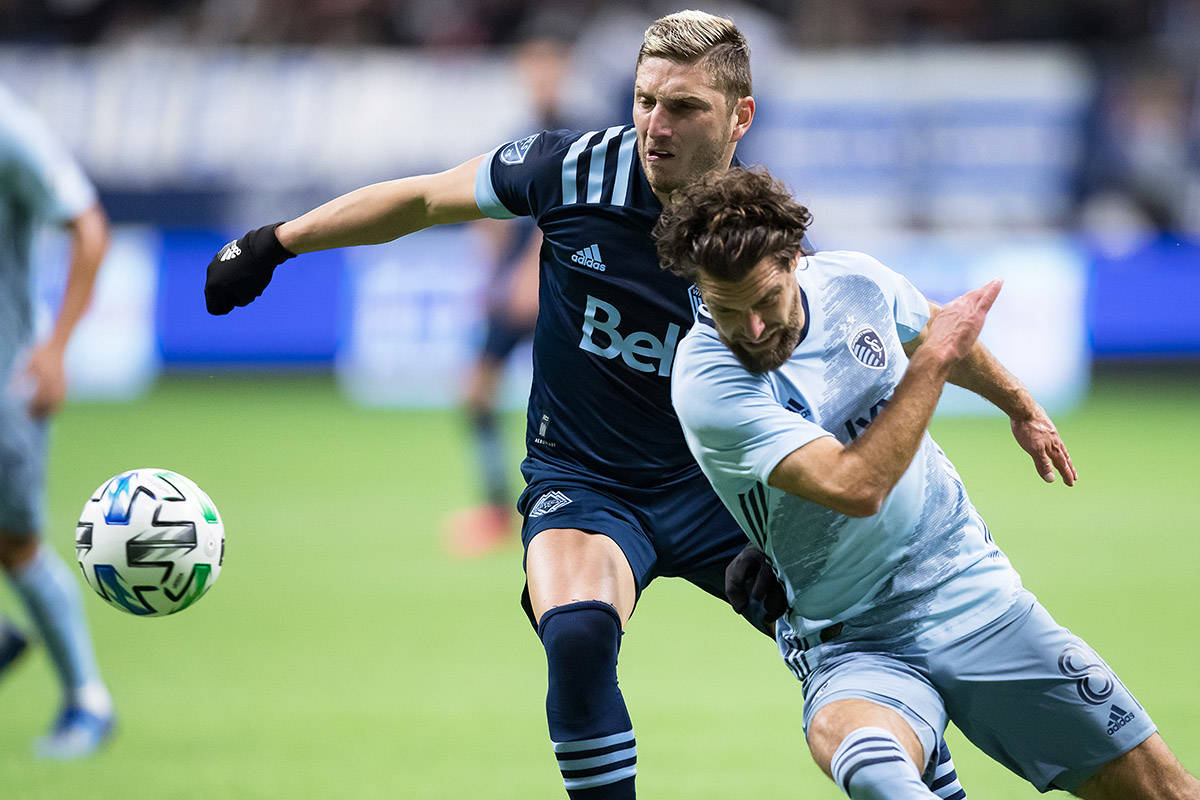 Vancouver Whitecaps’ David Milinkovic, back left, and Sporting Kansas City’s Graham Zusi vie for the ball during the first half of an MLS soccer game in Vancouver, B.C., Saturday, Feb. 29, 2020. THE CANADIAN PRESS/Darryl Dyck