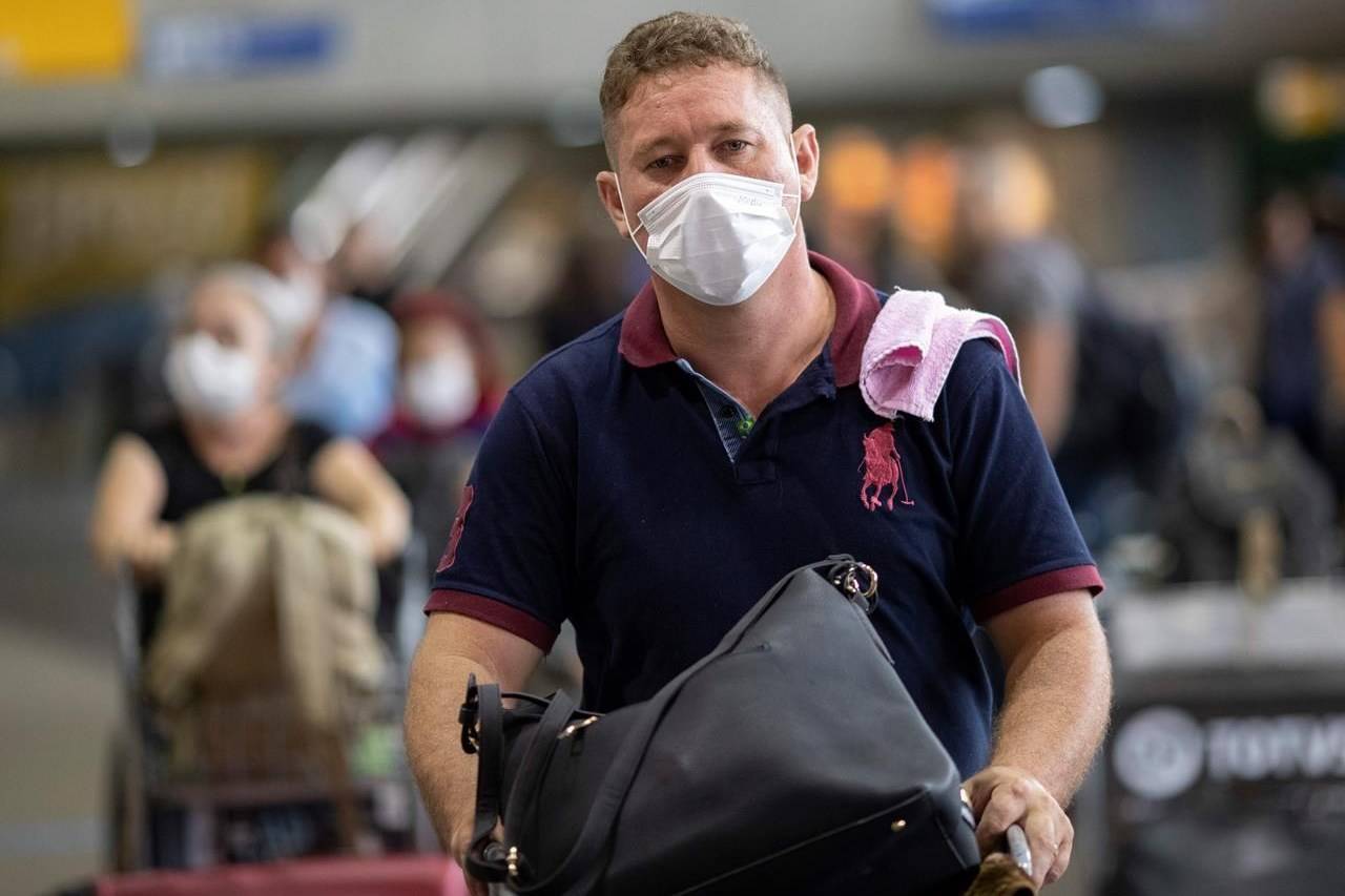 FILE - A man wears a mask as a precaution against the spread of the new coronavirus COVID-19 after his plane landed at the Sao Paulo International Airport in Sao Paulo, Brazil, Thursday, Feb. 27, 2020. (AP Photo/Andre Penner)
