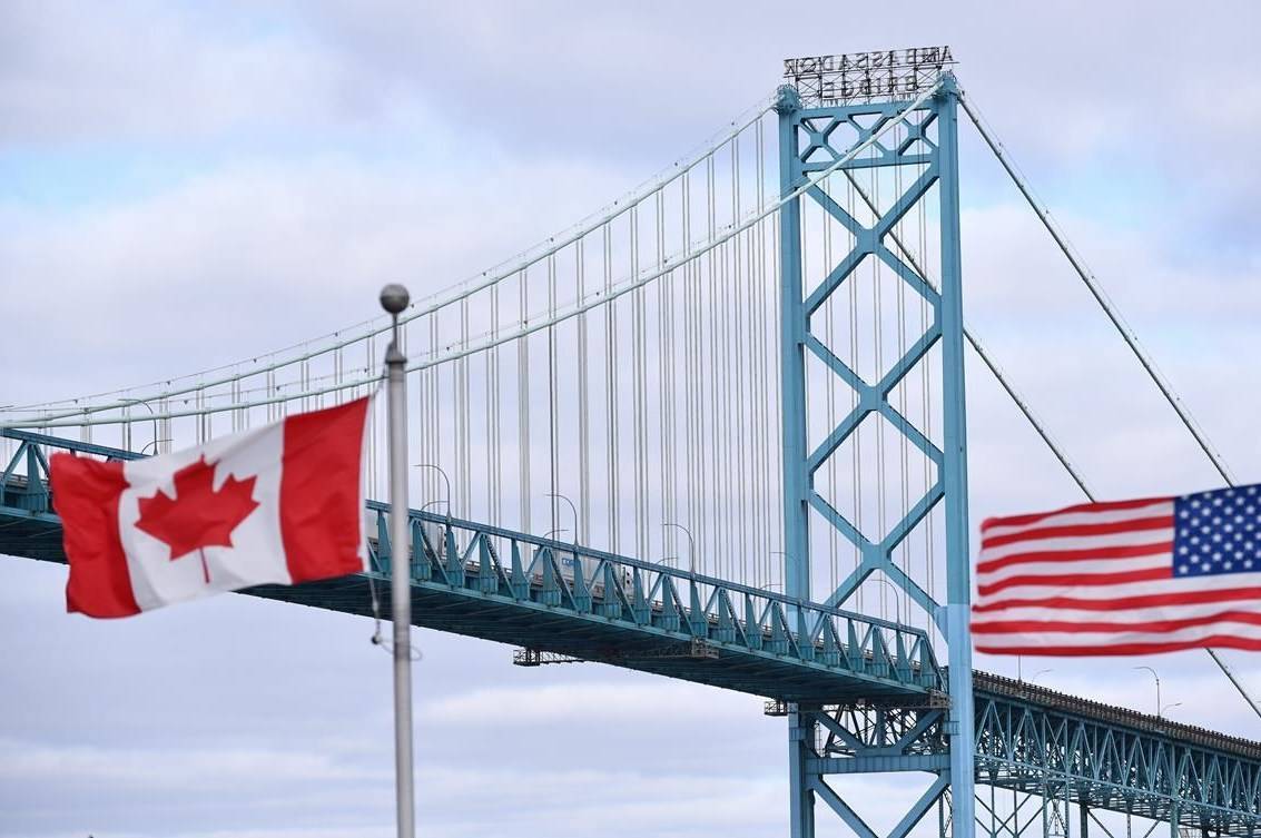Canadian and American flags fly near the Ambassador Bridge at the Canada-USA border crossing in Windsor, Ont. on Saturday, March 21, 2020. A new survey places the two neighbouring countries in very categories when it comes to their respective COVID-19 response. Canada ranks 13th, while the US ranks 70th in a survey by the Deep Knowledge Group. THE CANADIAN PRESS/Rob Gurdebeke