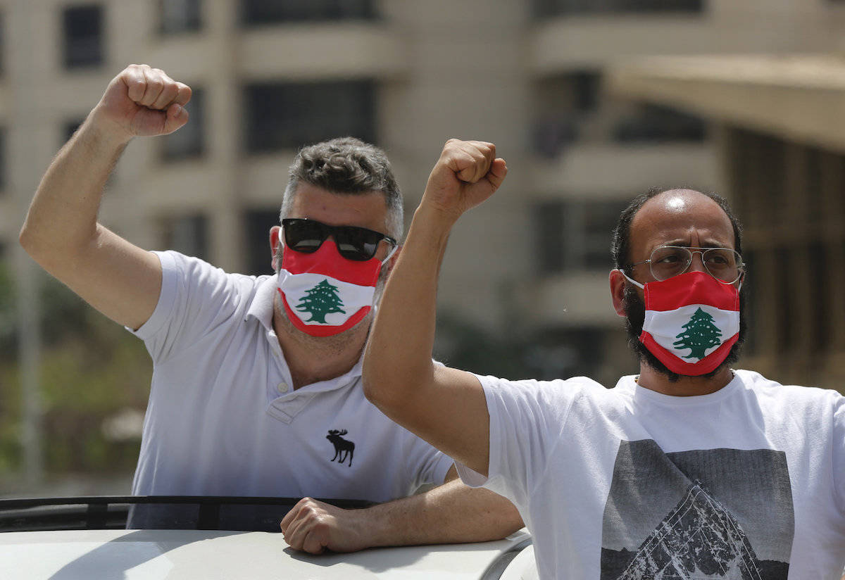 Anti-government protesters shout slogans, while wearing masks with the colors of the Lebanese flag to help curb the spread of the coronavirus, during a driving convoy protest through the streets to express rejection of the political leadership they blame for the economic and financial crisis, in Beirut, Lebanon, Tuesday, April 21, 2020. Lebanon’s parliament began Tuesday a three-day legislative session at a Beirut theater so that legislators can observe coronavirus social distancing measures, as protests against the country’s ruling elite in the crisis-hit country resumed. (AP Photo/Hussein Malla)