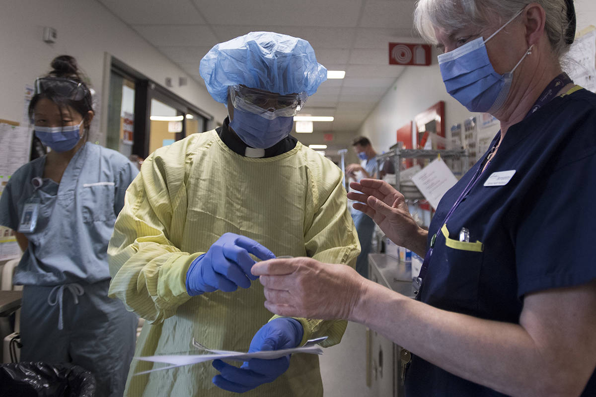 Father Victor Fernandes puts on personal protection equipment prior to visiting with a patient in the COVID-19 intensive care unit at St. Paul’s hospital in Vancouver, Tuesday, April 21, 2020. THE CANADIAN PRESS/Jonathan Hayward