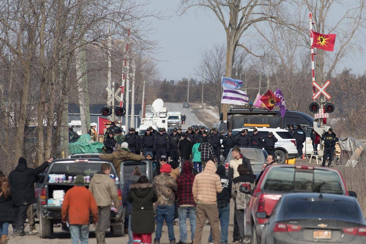 FILE – Protesters speak to Ontario Provincial Police officers at a rail blockade in Tyendinaga Mohawk Territory, near Belleville, Ont., on Monday Feb. 24, 2020, as they protest in solidarity with Wet’suwet’en Nation hereditary chiefs attempting to halt construction of a natural gas pipeline on their traditional territories. Analysts say Canadian National Railway Co. saw lower freight volumes last quarter due to rolling blockades that halted rail traffic across swathes of the country in February. THE CANADIAN PRESS/Lars Hagberg