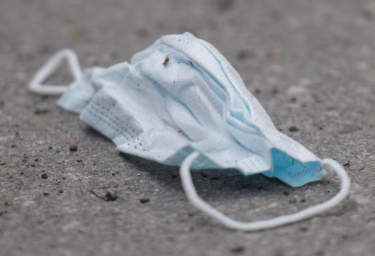 A discarded face mask is shown on a street next to a mobile COVID-19 testing clinic in Montreal, Sunday, May 17, 2020, as the COVID-19 pandemic continues in Canada and around the world. THE CANADIAN PRESS/Graham Hughes