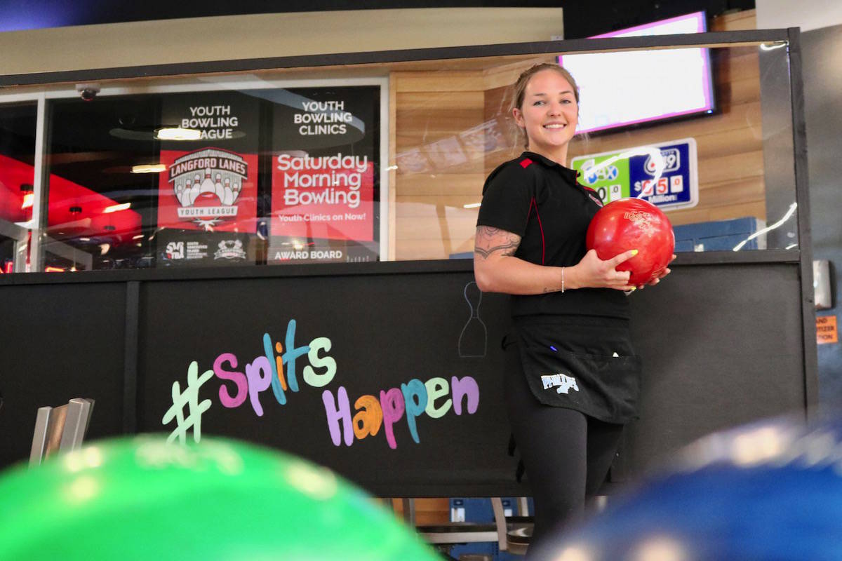 Langford Lanes employee Chloe Kehler (pictured) stands by a Plexiglas divider, a new installation at the bowling alley. They’re down to 10 lanes instead of 20. (Aaron Guillen/News Staff)