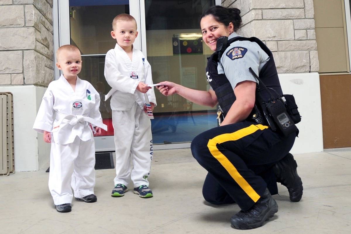 Anthony Fee, with his younger brother Asher by his side, presents Oceanside RCMP’s youth officer Danielle Swanson the money he collected on his fifth birthday, to be donated to the COPS for Cancer. (Michael Briones photo)