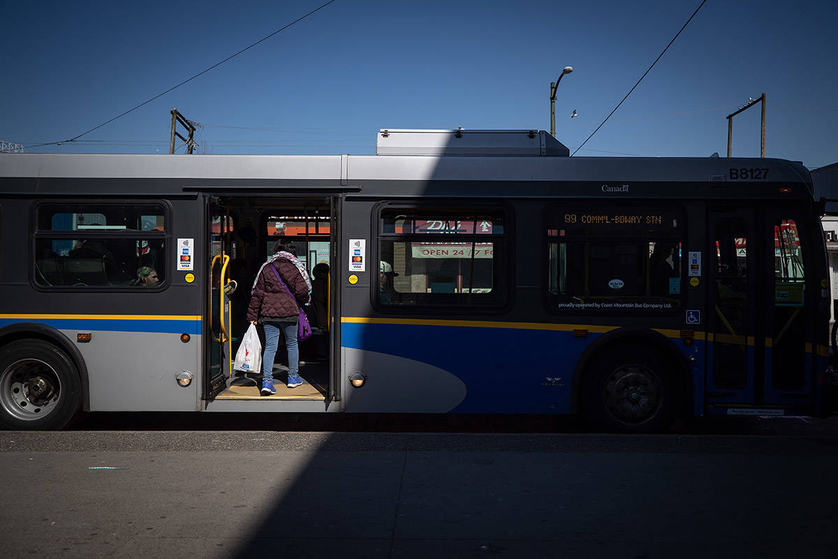 A woman boards a transit bus through rear doors, in Vancouver, on Friday, March 20, 2020. THE CANADIAN PRESS/Darryl Dyck