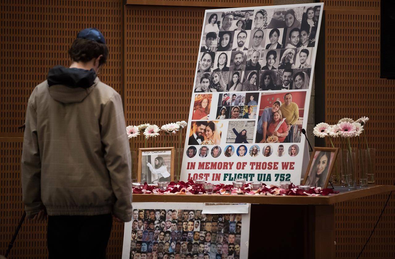 A man pauses to look at photographs of some of the people who died in the downing of Ukrainian Airlines Flight 752 in Iran, during a vigil for the victims of the flight at the Har El synagogue in West Vancouver on January 19, 2020. THE CANADIAN PRESS/Darryl Dyck