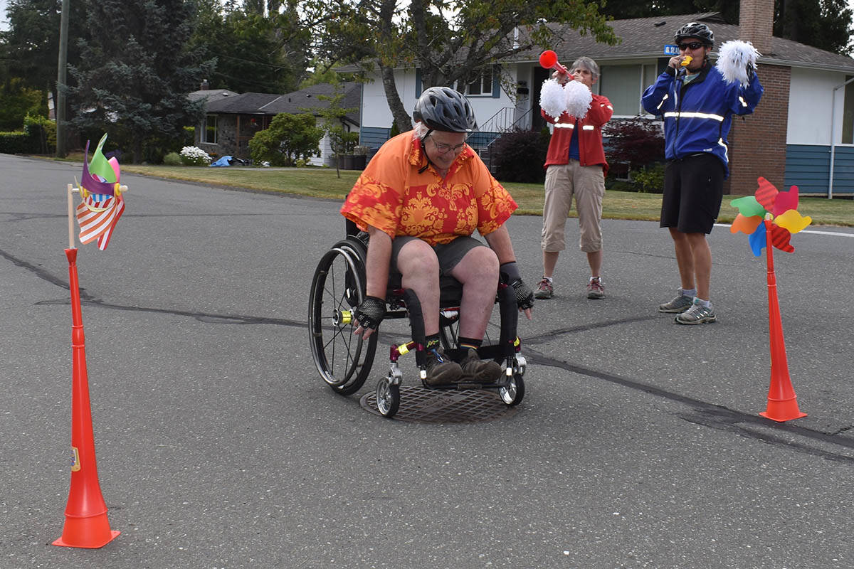 Karin Kratz crosses the finish line marking the completion of her half-marathon, with friends Joan Gillies (in red) and Heather Blyth there to cheer her on. Photo by Terry Farrell
